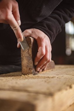 Erkek marangoz antika bir atölyede eski ahşap üzerinde çalışıyor..