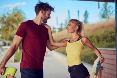 Nehir kenarındaki kentsel çevrede koşan / egzersiz yapan modern kadın ve erkek.