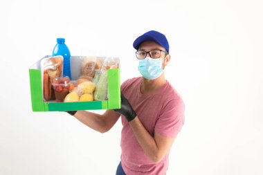 Koruyucu maskeli teslimatçı. Bakkaliye kutusuyla birlikte..