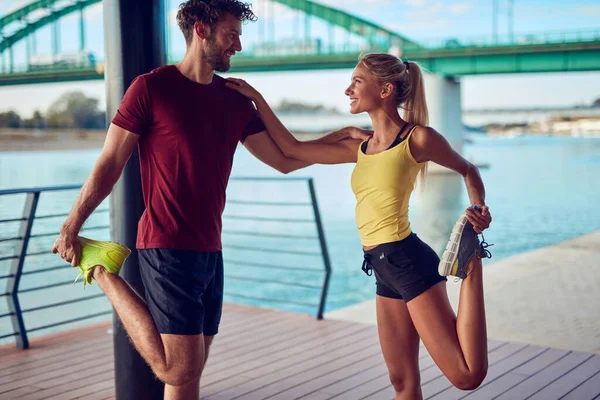 Nehir kenarındaki kentsel çevrede koşan / egzersiz yapan modern kadın ve erkek.