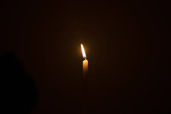 Una luce di candela illuminata in uno sfondo nero . — Foto Stock