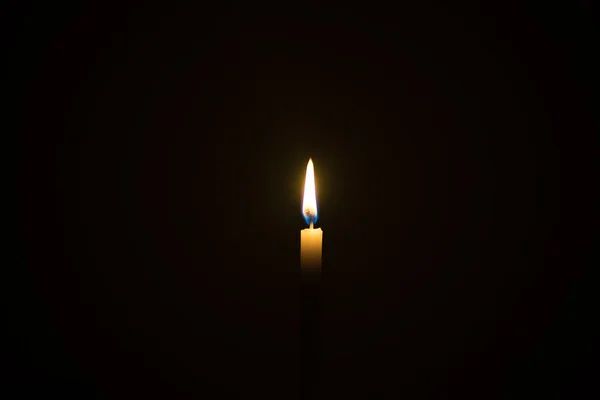 Jedno światło świecy oświetlone w czarnym tle. — Zdjęcie stockowe