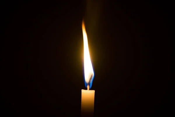 Eine Kerze beleuchtet in einem schwarzen Hintergrund. — Stockfoto