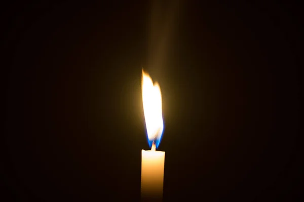 Luz de una vela iluminada en un fondo negro . — Foto de Stock