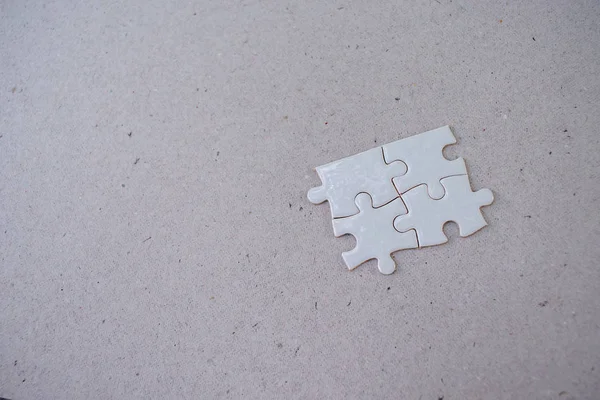 Rompecabezas blanco de cuatro piezas sobre un fondo de papel —  Fotos de Stock