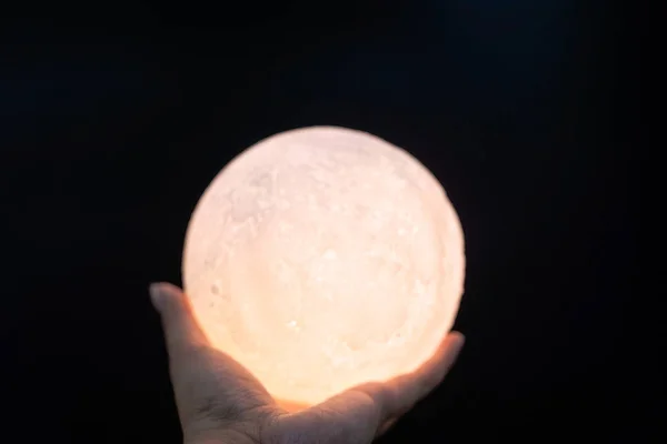 En bild på en hand som håller en modell av månen på natten — Stockfoto