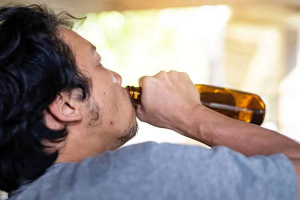Egy részeg férfi felvesz egy üveget, hogy igyon.. — Stock Fotó