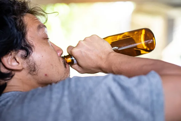 Portrait A drunken man is picking up a bottle to drink. — Stock Photo, Image