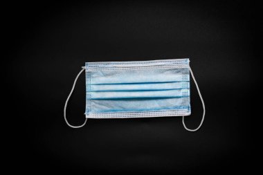 Gribi ve diğer hastalıkları önlemek için siyah arka planda mavi tıbbi maske. Corona virüsünün yayılmasını engeller..