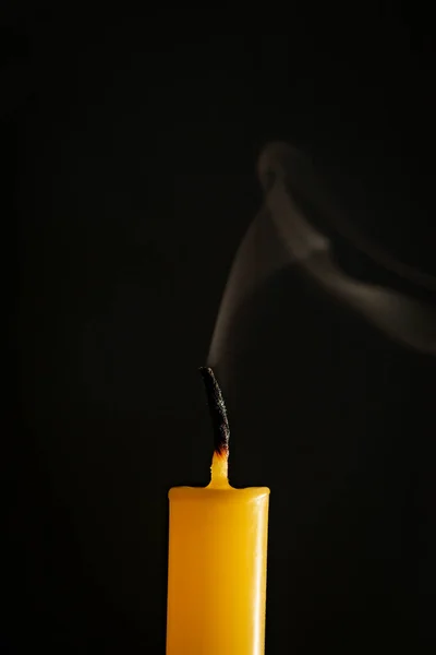 黄色のろうそくが消え 黒い背景で煙が発生します — ストック写真