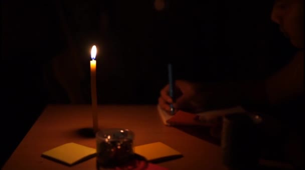 夜のろうそくの映像とテーブルの上に書く人々 — ストック動画