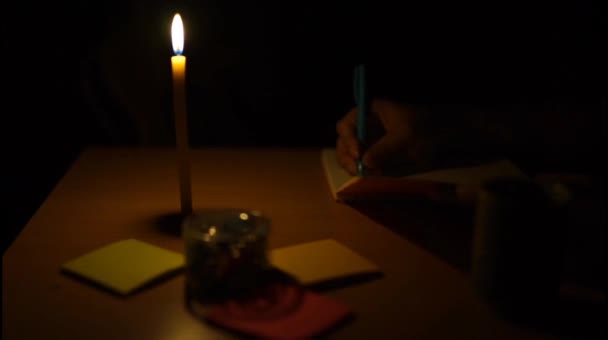 夜のろうそくの映像とテーブルの上に書く人々 — ストック動画