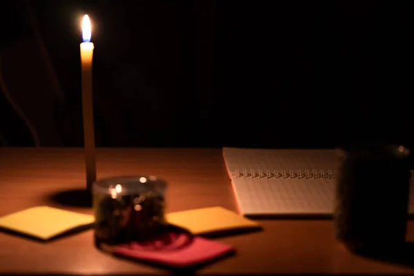 テーブルの上に置かれたノートと紙クリップのクローズアップ写真とキャンドルからのオレンジ色の光 — ストック写真