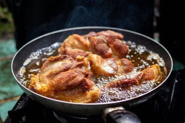 Kızartma tavasında domuz eti pişirirken yakın plan çekimde sıcak yağ var ve lezzetli görünüyor..