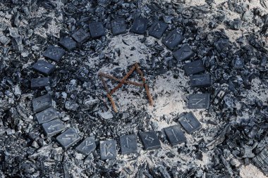 24 İskandinav rünü çemberinin içinde küller üzerinde İskandinav rünü Mannaz.