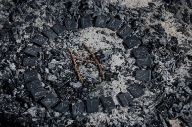 İskandinav rünü Hagalaz, 24 İskandinav rününden oluşan çemberin içinde küller üzerinde.