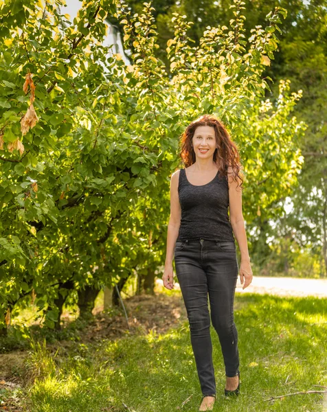 漂亮的红色女人享受乡村的自然 而走在苹果园在秋天的季节 — 图库照片