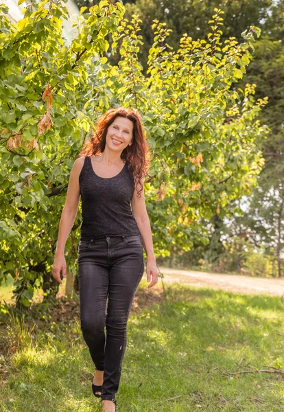 黑衣更年期妇女享受乡村的自然 而走在苹果园在秋天 — 图库照片