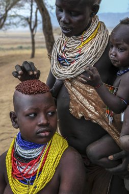 OMO Vadisi, Etiyopya - 26 Ocak: Kimliği belirsiz bir kadın olan geleneksel takı Karo kabile ve oğlu ile Karo Etiyopya'da 26 Ocak 2018 üzerinde arka planda tipik evleri.