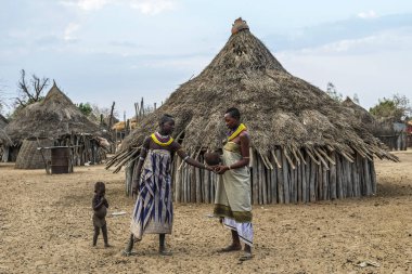 OMO Vadisi, Etiyopya - 26 Ocak: İki kimliği belirsiz kadın köylerine arka planda Karo tipik evleri ile 26 Ocak 2018 Omo Vadisi, Etiyopya konuşan Karo kabilesinin.