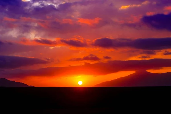 Scarlet sunset in the steppe with purple clouds