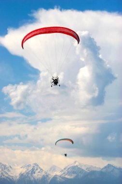 Two paragliders with red parachutes over the mountains near Almaty in Kazakhstan clipart