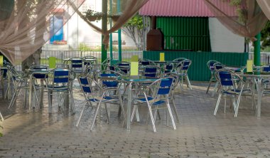 Mavi metal masalar ve sandalyeler bir yaz kafesinde, dışarıda insanlar olmadan parkta.