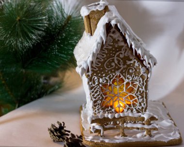 Noel ağacı altında karamel pencereli beyaz kremayla süslenmiş Noel kurabiyesi evi. 