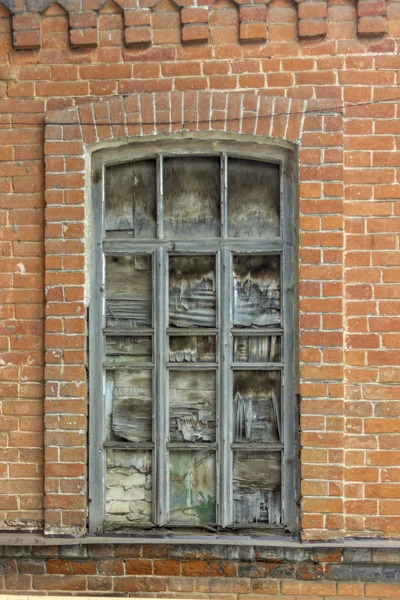 antique window with broken glass in a brick wall