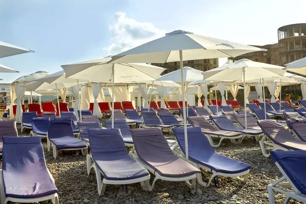 Spiaggia Ghiaia Con Lettini Ombrelloni Contro Cielo Blu Foto Stock