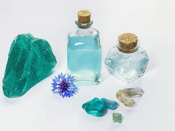 Cornflower flower and blue water or aromatherapy oil in glass bottle. Natural mineral crystals on white background