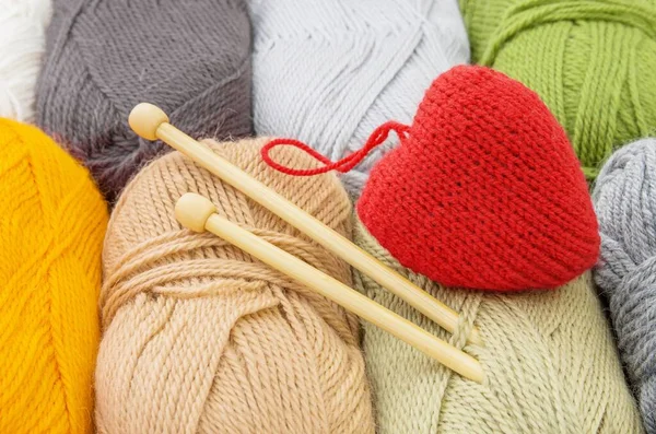 Color  yarn skeins, knitting needles and red heart, close up. The concept of knitting and love.Valentines day