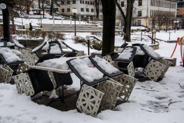 Bulgaristan 'ın Smolyan kentinde kışın karla kaplı kafe sandalyeleri ve masaları. Şehirde kış.