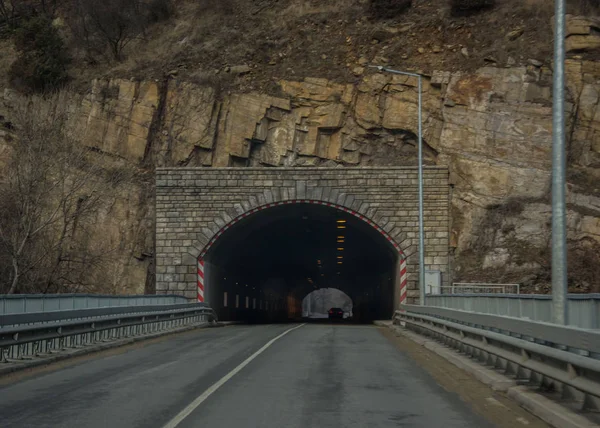 Bulgaristan 'daki dağlardaki tünelin sonu, kayalıklardan geçen araba yolu, giriş, etrafını çevreleyen karanlık duvarlar ve tepesi aydınlık