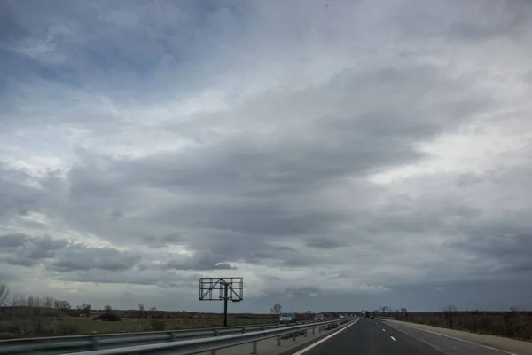 Arabaları ve kamyonları olan Bulgar otoyolu, yan taraflarında yol işaretleri olan asfalt yol, sisli hava