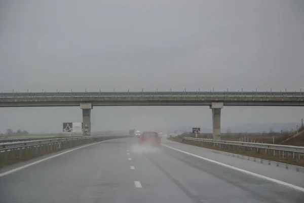 Passing under a bridge on an highway, rainy days, car driving through water from the storm, bad weather