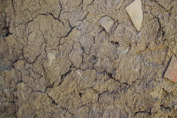 Old cracked wall made from mud and hay, exterior background, grunge texture with cracks for designs