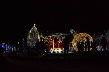 Varna, Bulgaristan - 7 Aralık 2019 - Renkli Noel süslemeleri ve geceleri ışıklar, yeni yıl tatili dekorasyonu, Varna şehir meydanı, insanların silüetleri