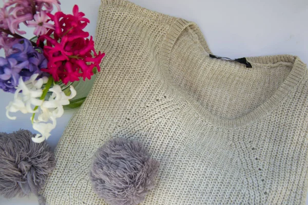 Close-up of knitted blouse and hat with pom pom, winter concept, green cactus, colorful hyacinth flowers in a vase