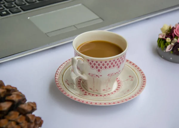 Coffee in the office, close-up of the desk with different objects, beautiful decorated cup with hot beverage, business concept