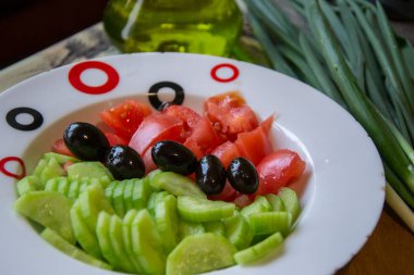 Taze sebzeli salata, salatalık, domates ve baharat tabağında siyah zeytin, sağlıklı yemek için malzemeler.