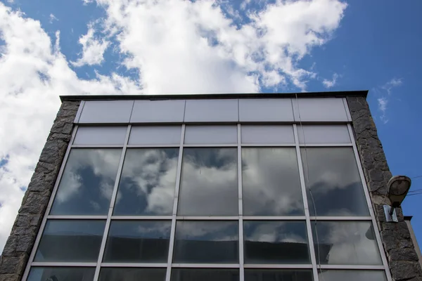 Beautiful white clouds and blue sky reflecting in the windows of a building, architecture. Clouds reflection