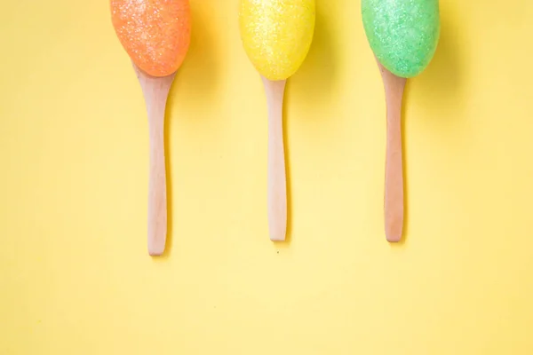 Three Colorful Easter Eggs Pale Yellow Background Egg Wooden Spoons — Stock Photo, Image