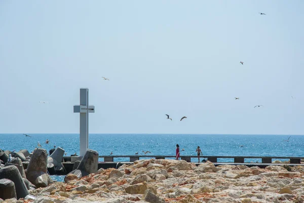 湾の上の大きなコンクリートの十字架の景色 人々が歩いて鳥が飛んで 青い海と空 防波堤 夏の季節 — ストック写真