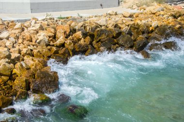Güzel turkuaz su dalgaları kayalıklara vuruyor, beyaz köpük, yaz mevsimi sahnesi, doğa, kayalar.