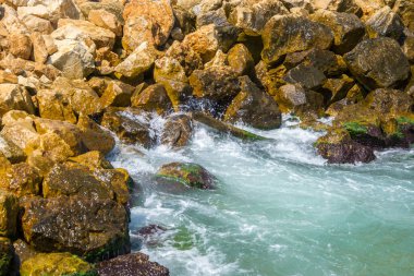 Güzel turkuaz su dalgaları kayalıklara vuruyor, beyaz köpük, yaz mevsimi sahnesi, doğa, kayalar.