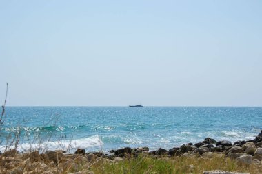 Güzel vahşi sahil manzarası ve arka planda yat güneşli bir gün, su dalgaları ve uçurumlar, doğa yaz manzarası.