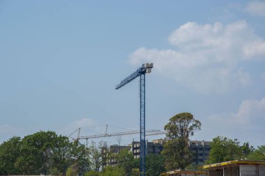 Endüstriyel yapı, vinçler ve binalar şehirde, ağaçlar ve mavi gökyüzü