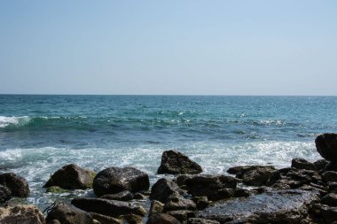 Güzel vahşi sahil manzarası, güneşli bir gün, kayalıklara vuran su dalgaları, yaz manzarası.