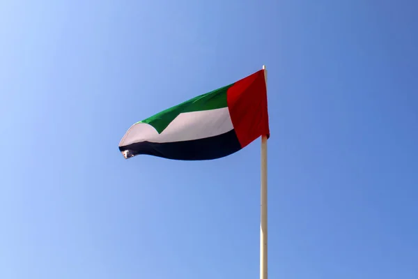 United Arab Emirates flag waving on blue sky background. Close up, isolated. UAE flag. Emirates national day. Flag day